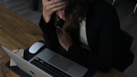 A person sitting at a desk with an AI interview coach interface, looking stressed and unsure